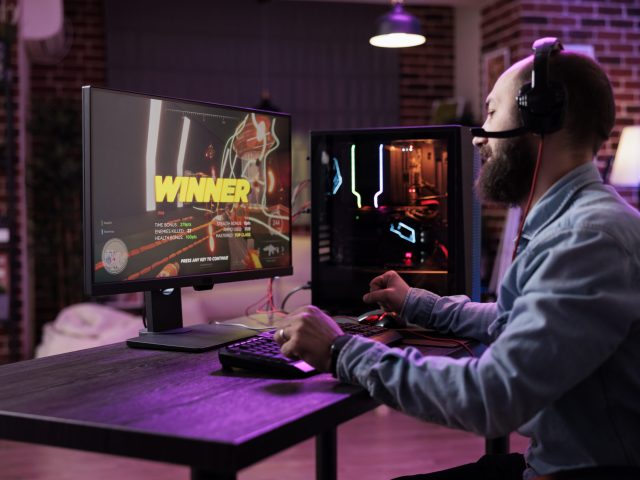 Young person winning action video games on computer, playing online gaming championship. Male player celebrating gameplay win, feeling happy about rpg tournament on modern computer.